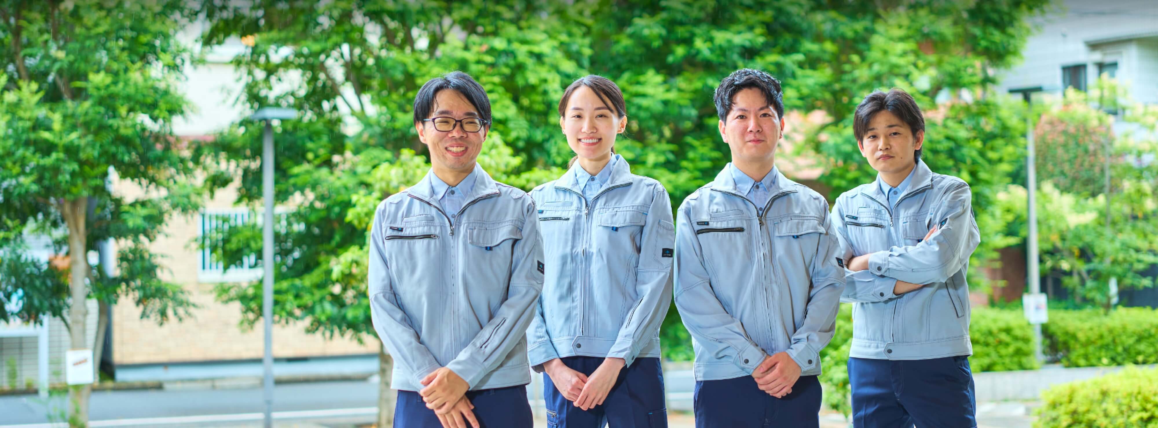 屋外にて作業着を着用し整列する社員